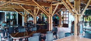 A restaurant with bamboo ceiling structures, tables, and chairs. - cabañas hotel villa lucia (Calarcá)
