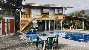 A two-story house with a pool, outdoor seating, and a staircase leading to a balcony. - cabañas hotel villa lucia (Calarcá)