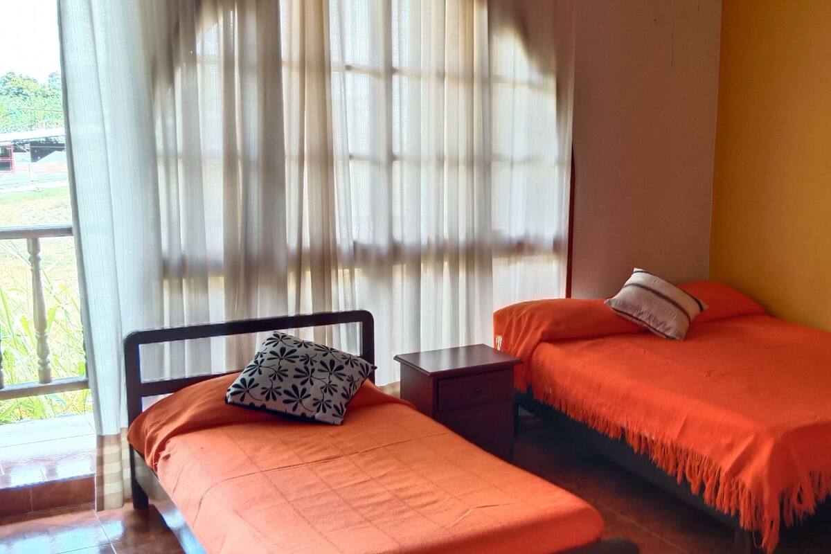 A room with two beds, a nightstand, a lamp, and a large abstract painting on the wall.