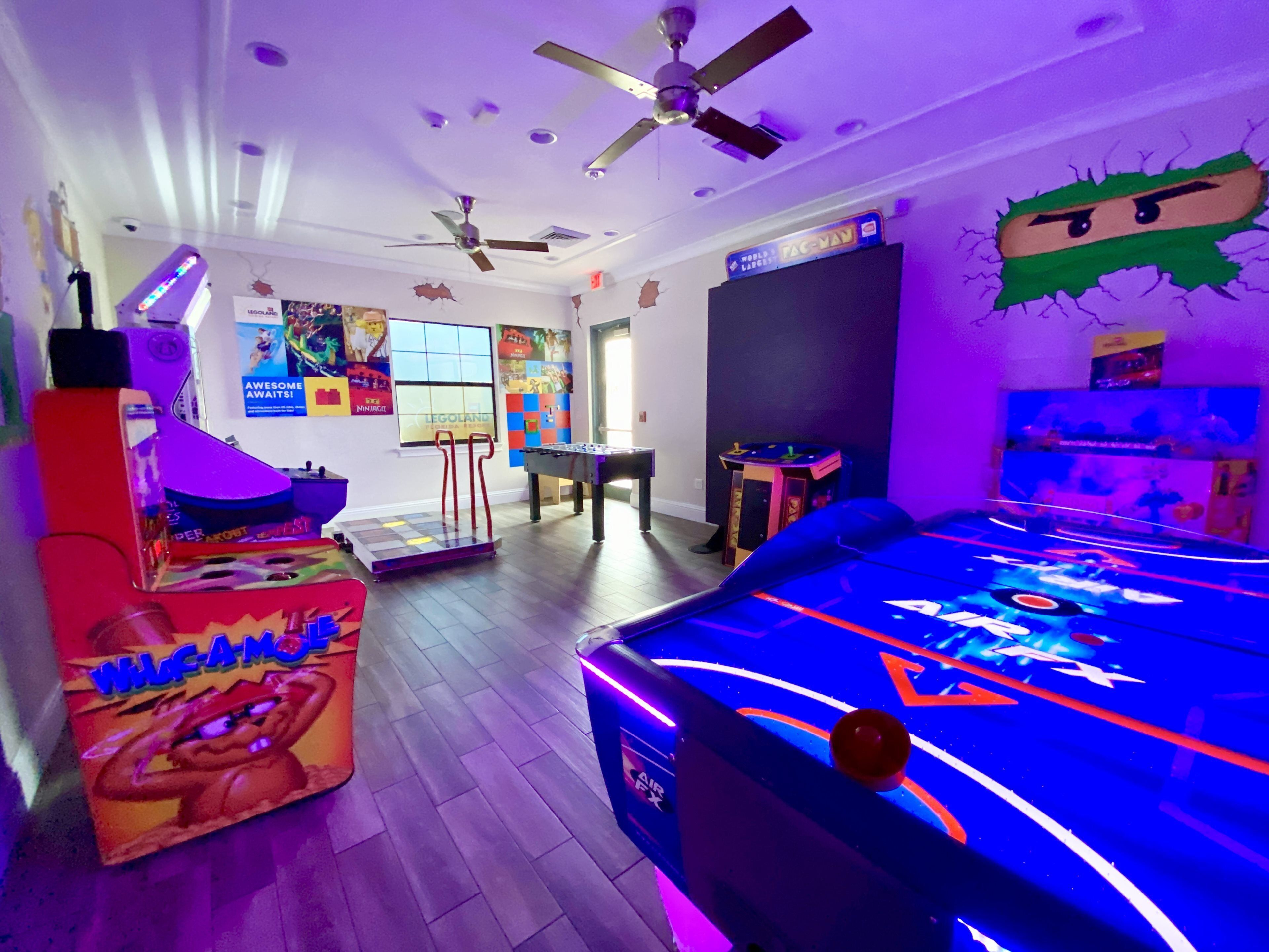 A room with a foosball table, a pool table, and a ceiling fan.