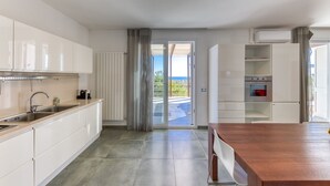 A modern kitchen with a wooden island, built-in cabinets, and a view to the outside. - Pool villa near the beaches w/ fantastic sea view (Torre Pali)