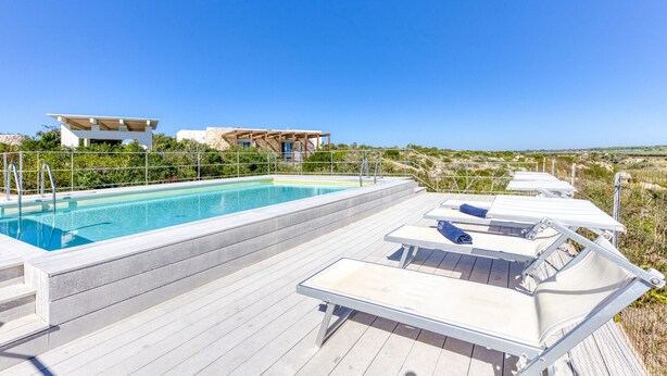 A rooftop swimming pool with lounge chairs and a modern building in the background. - Pool villa near the beaches w/ fantastic sea view (Torre Pali)