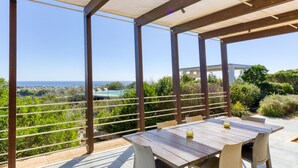 An outdoor patio with a wooden table and chairs, overlooking a pool and lush greenery. - Pool villa near the beaches w/ fantastic sea view (Torre Pali)