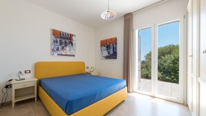 A bedroom with a bed, a desk, and two paintings on the wall.