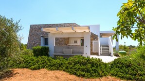 A modern house with a stone facade, a covered patio, and a view of the surrounding greenery.