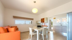 A modern kitchen with white cabinets, a dining table with chairs, and a bright pendant light.