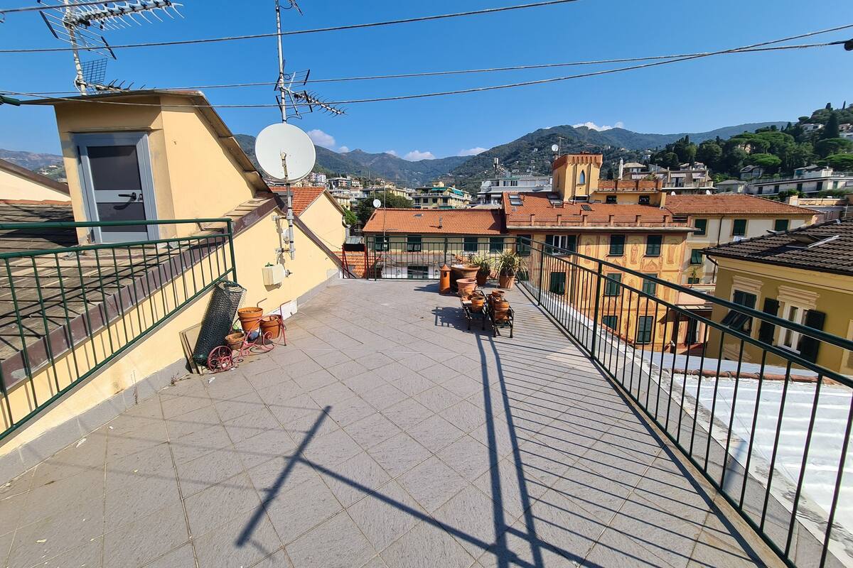 A rooftop terrace with a view of a cityscape, including buildings and mountains.