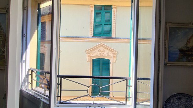 An open balcony with a view of a building with green shutters and a decorative entrance. - Casa Vittoria by PortofinoVacanze (Rapallo)