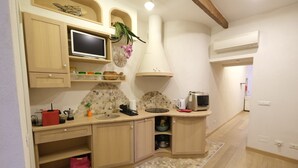 A kitchen with a stone backsplash, wooden cabinets, a built-in microwave, and a sink. - Casa Vittoria by PortofinoVacanze (Rapallo)