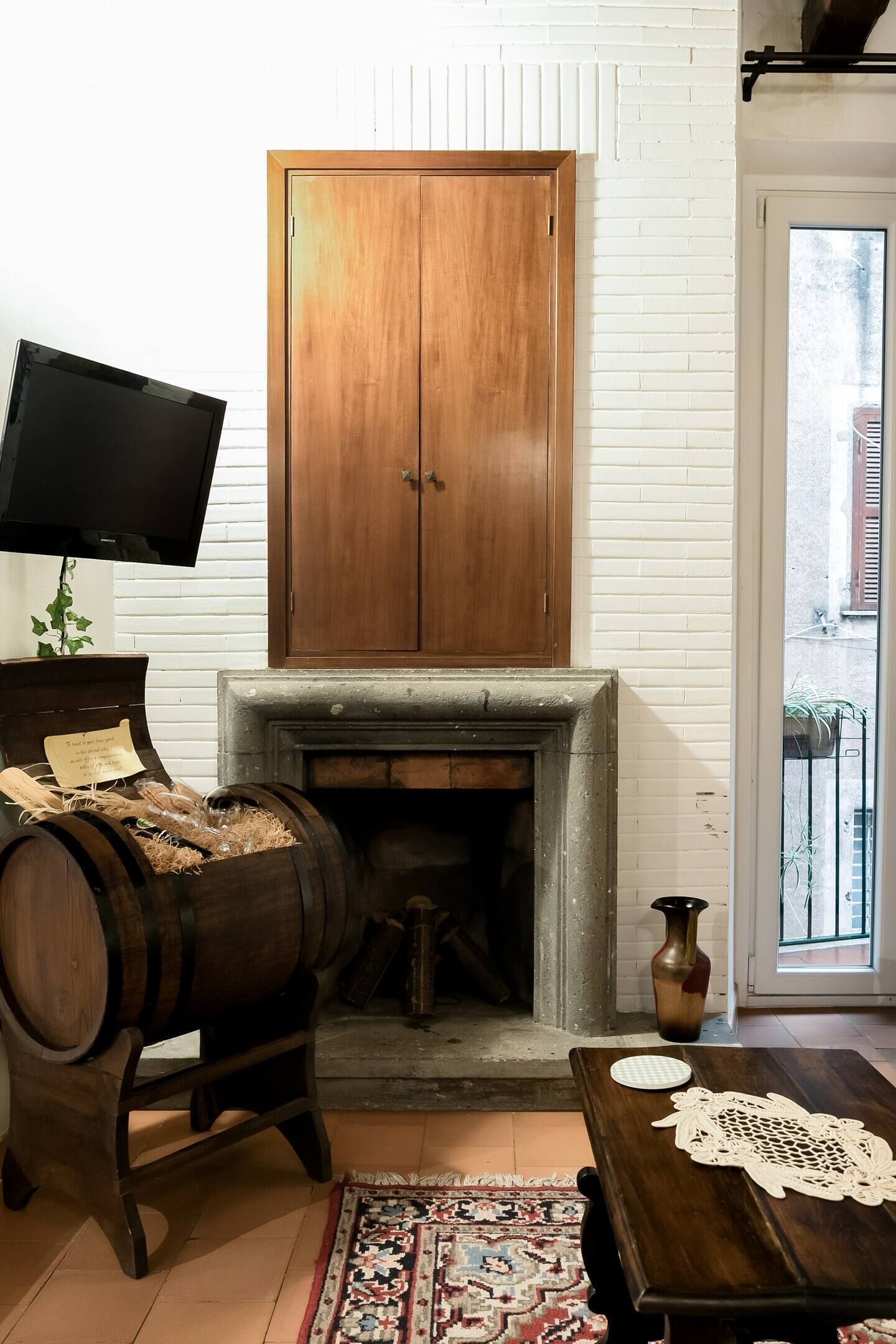 A room with a wooden cabinet, a fireplace, a television, and a rustic rug.
