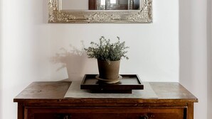 A mirror with an ornate frame, a wooden dresser below, and a potted plant on top. - La Trasteverina apartment (Roma)