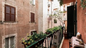 A narrow alley with buildings on either side, featuring balconies with potted plants and a table with a tablecloth. - La Trasteverina apartment (Roma)