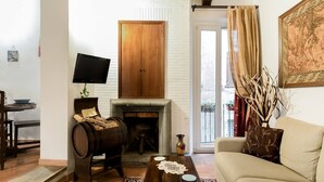 A cozy living room with a fireplace, wooden barrel, sofa, and a television. - La Trasteverina apartment (Roma)