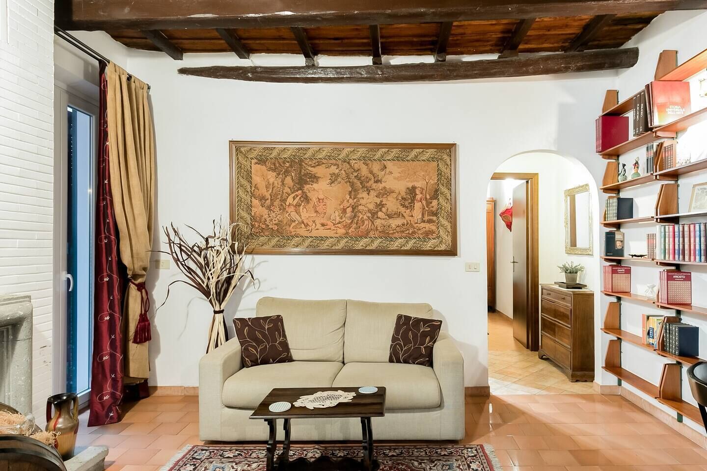 Una sala de estar con un sofá beige, una mesa de centro, un cuadro grande enmarcados, una estantería y una chimenea.