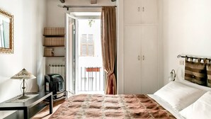 A bedroom with a bed, a desk with a lamp, a wardrobe, and a view of the outside. - La Trasteverina apartment (Roma)
