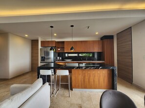 A modern kitchen with wooden cabinets, a black countertop, and two pendant lights.