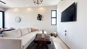 A modern living room with a sofa, coffee table, and a flat-screen TV mounted on the wall.