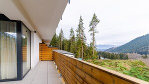 A modern balcony with a wooden railing overlooking a mountainous landscape. - Spa & Wellness Hotel Fitak (Liptovský Ján)