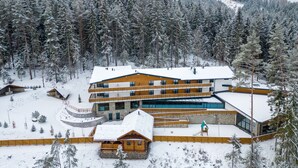 A modern lodge with multiple floors, wooden exterior, and a snow-covered landscape. - Spa & Wellness Hotel Fitak (Liptovský Ján)