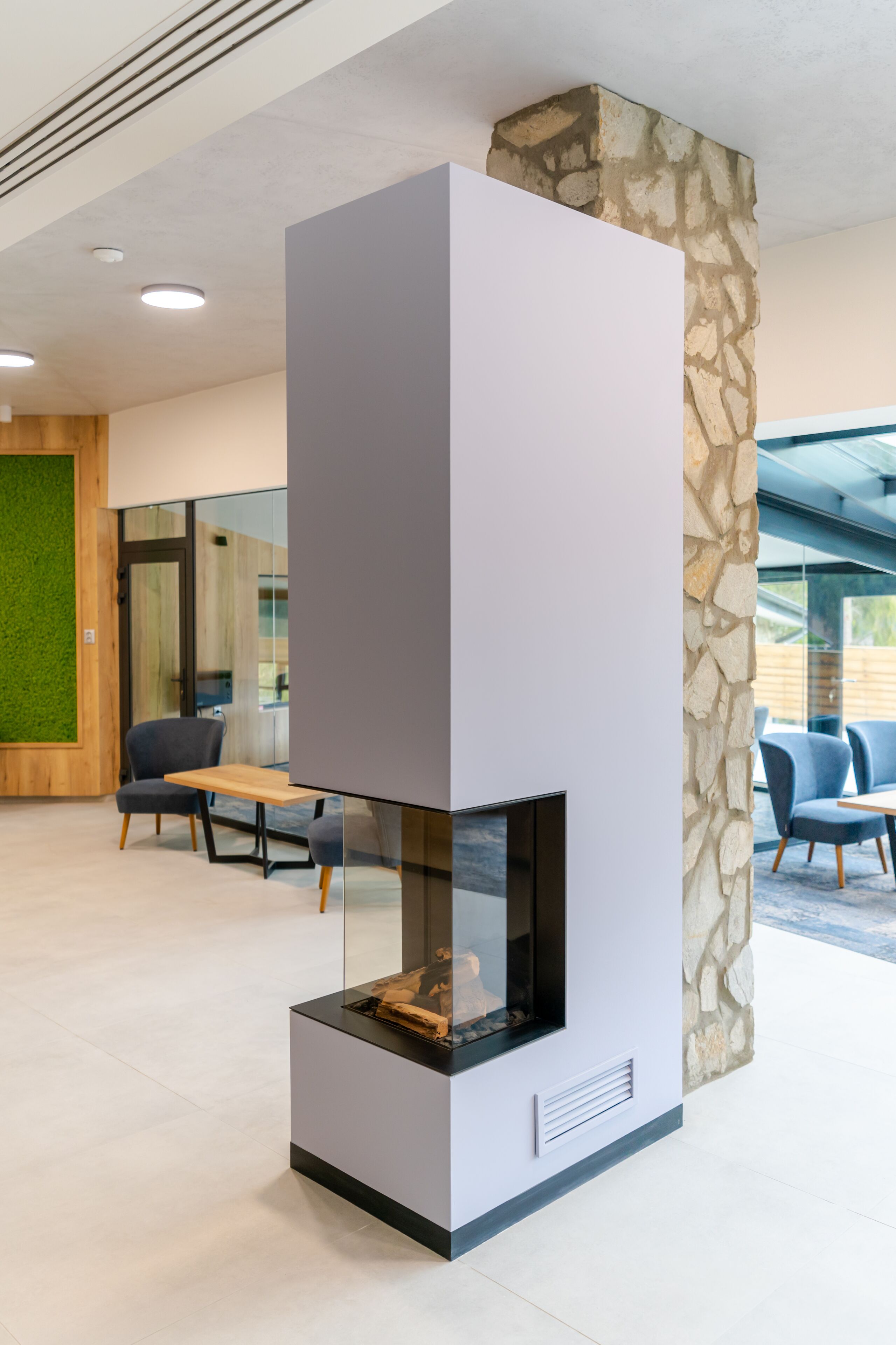 A modern interior with a stone accent wall, a built-in fireplace, and seating areas.