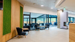 A modern indoor space with wooden paneling, green wall accents, and a stone pillar. - Spa & Wellness Hotel Fitak (Liptovský Ján)