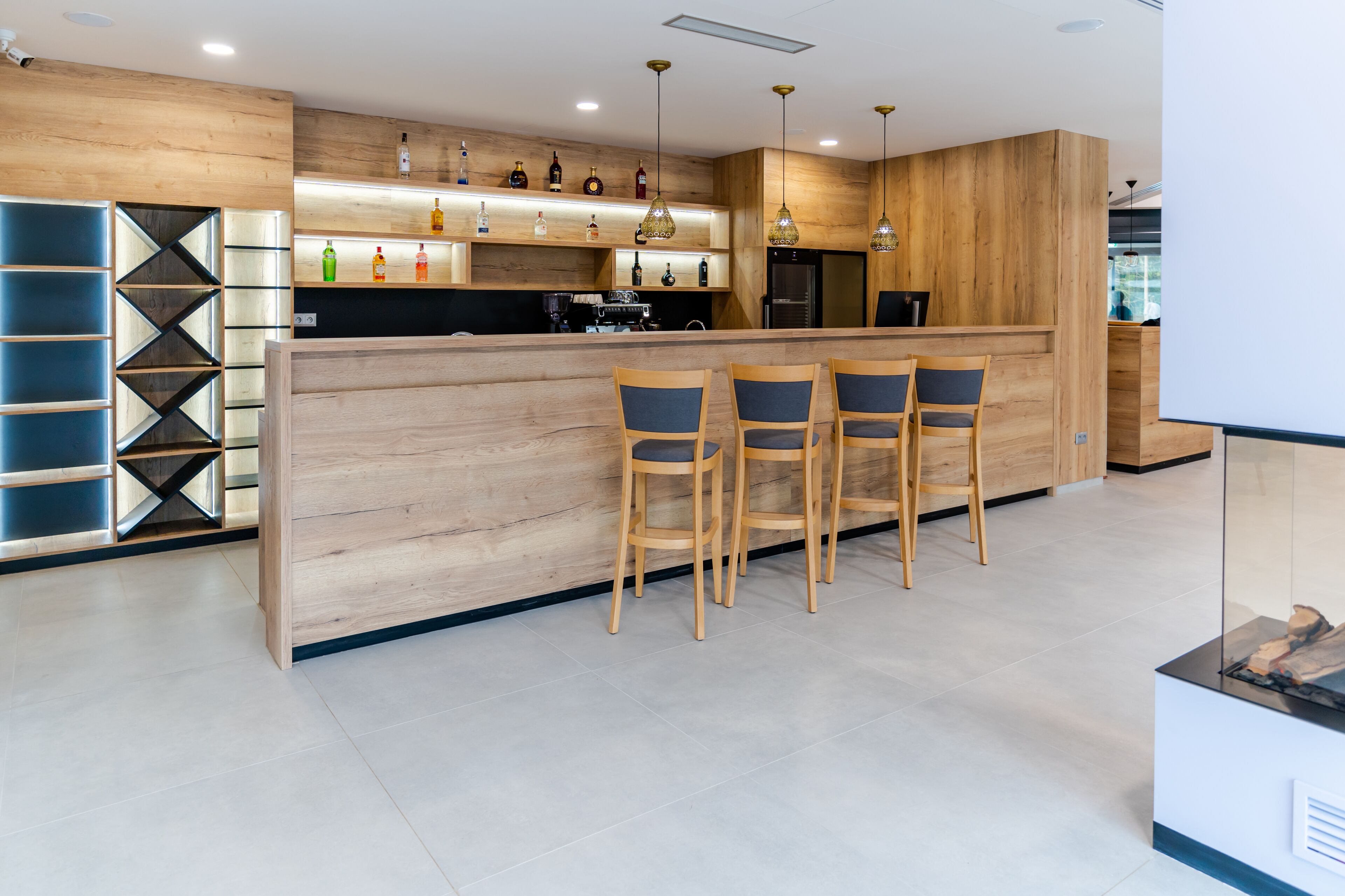 Una cocina moderna con muebles de madera, una zona de bar con taburetes y una cafetera integrada.