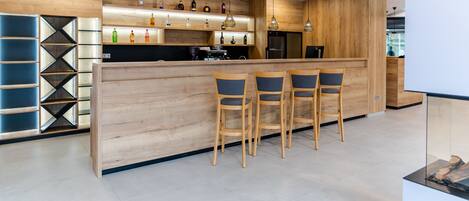 Una cocina moderna con muebles de madera, una zona de bar con taburetes y una cafetera integrada.