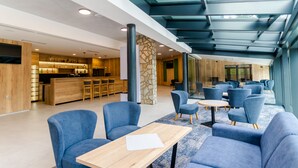 A modern hotel lobby with seating areas, a reception desk, and a bar/lounge area. - Spa & Wellness Hotel Fitak (Liptovský Ján)