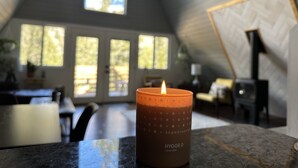 A candle on a table in a room with a sloped ceiling and large windows.
