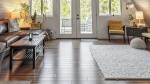 A spacious attic room with a sloped ceiling, large windows, and a cozy seating area with a sofa and a bench.