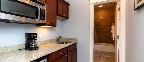 A kitchen with a stainless steel microwave, a coffee maker, and a sink.