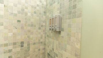Un baño con pared de azulejos y dispensador de jabón.