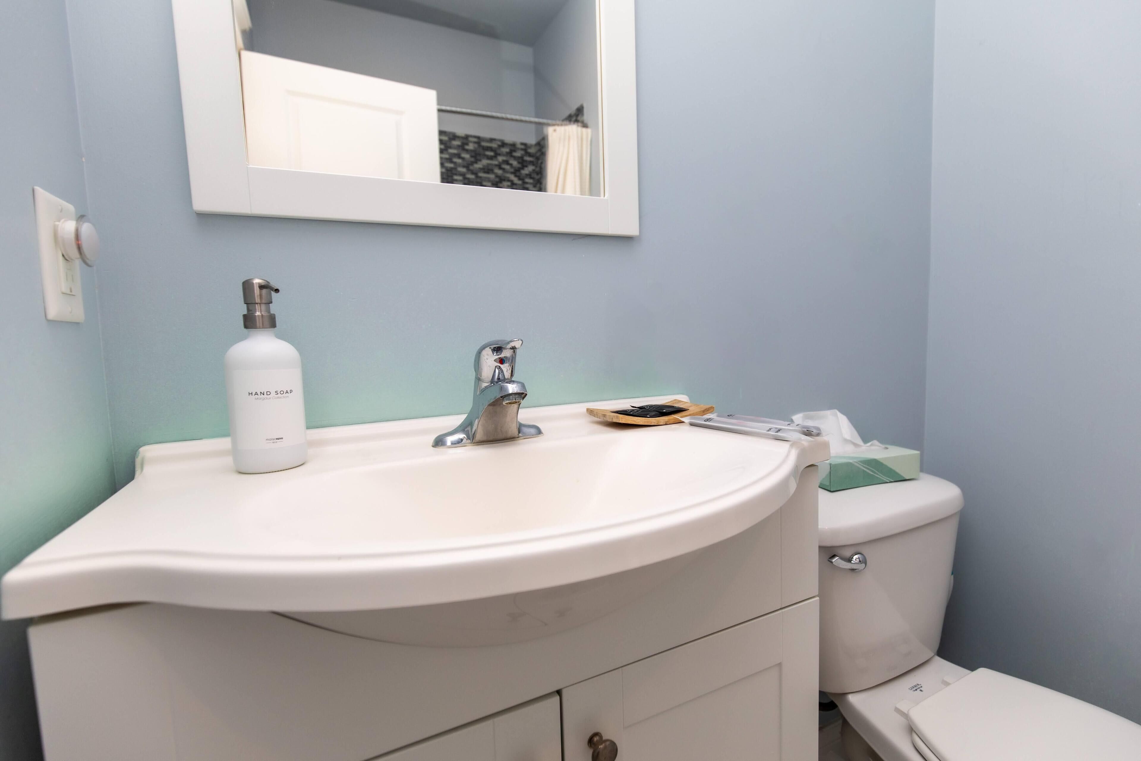 A bathroom with a white sink, a mirror above it, and a toilet.