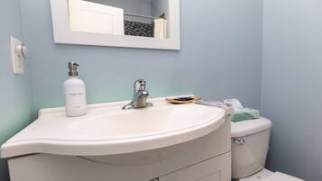 A bathroom with a white sink, a mirror above it, and a toilet.