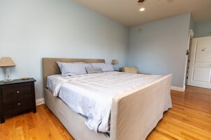 Un dormitorio con cama, mesita de noche y puerta.