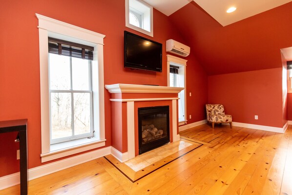 A room with a fireplace, a television mounted above it, and a chair.