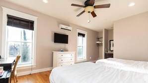 A bedroom with a bed, a desk, a chair, a TV, and a ceiling fan. - Furness Mansion (Chesterton)