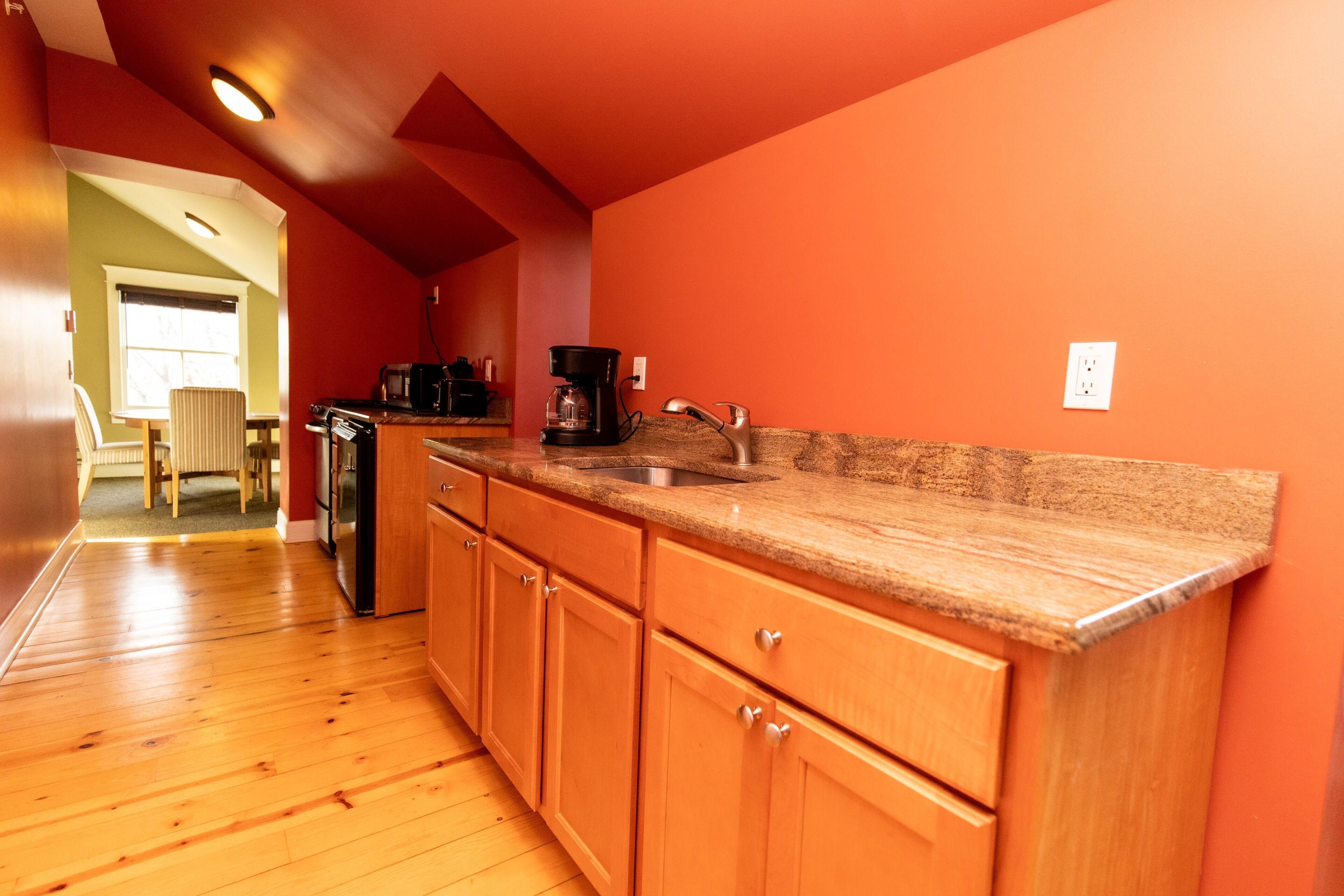 A kitchen with wooden cabinets, a granite countertop, and a coffee maker.