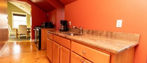 A kitchen with wooden cabinets, a granite countertop, and a coffee maker.