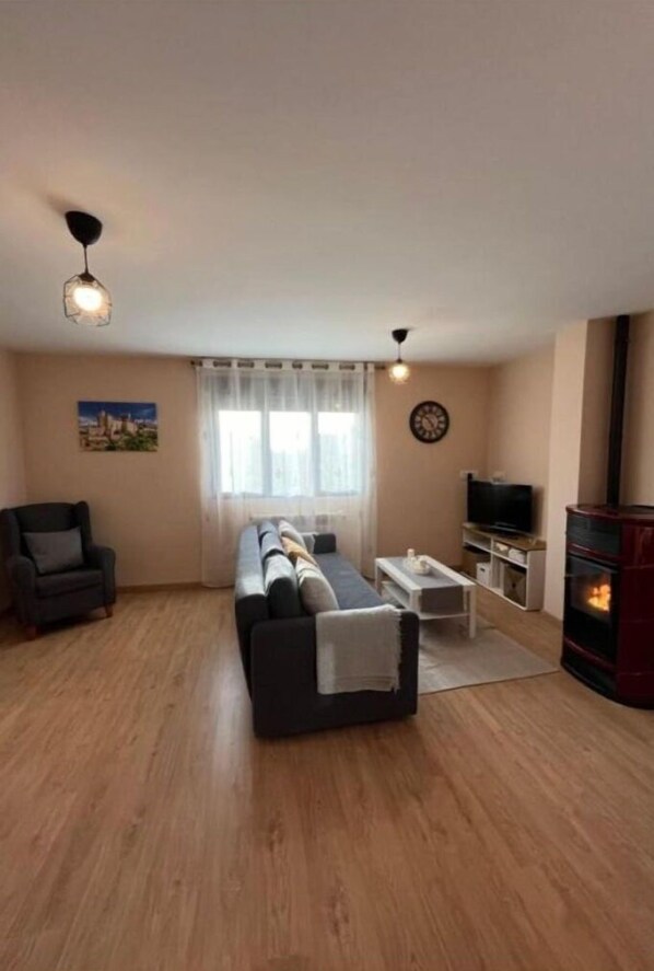 Uma sala de estar com sofá, televisão, lareira e um quadro na parede.