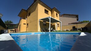 Ein Swimmingpool mit überdachtem Patio, ein gelbes Gebäude und ein klarer, blauer Himmel.