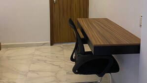 A conference room with a wooden table, black chairs, a TV mounted on the wall, and a wooden door. - HOTEL CAMELINAS EXPRESS (Lazaro Cardenas)