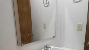 A bathroom with a white sink, mirror, and wooden door. - HOTEL CAMELINAS EXPRESS (Lazaro Cardenas)