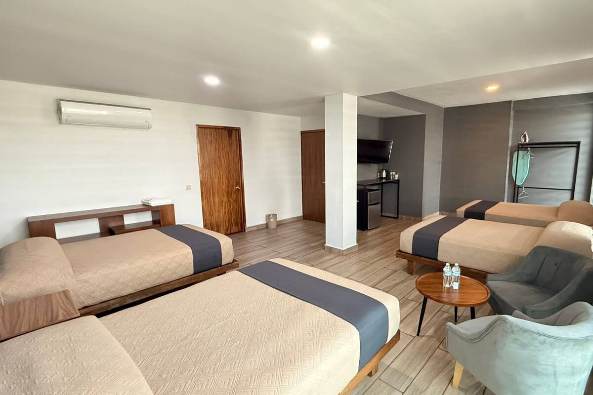 A hotel room with two beds, a sofa, a small table, and a TV.