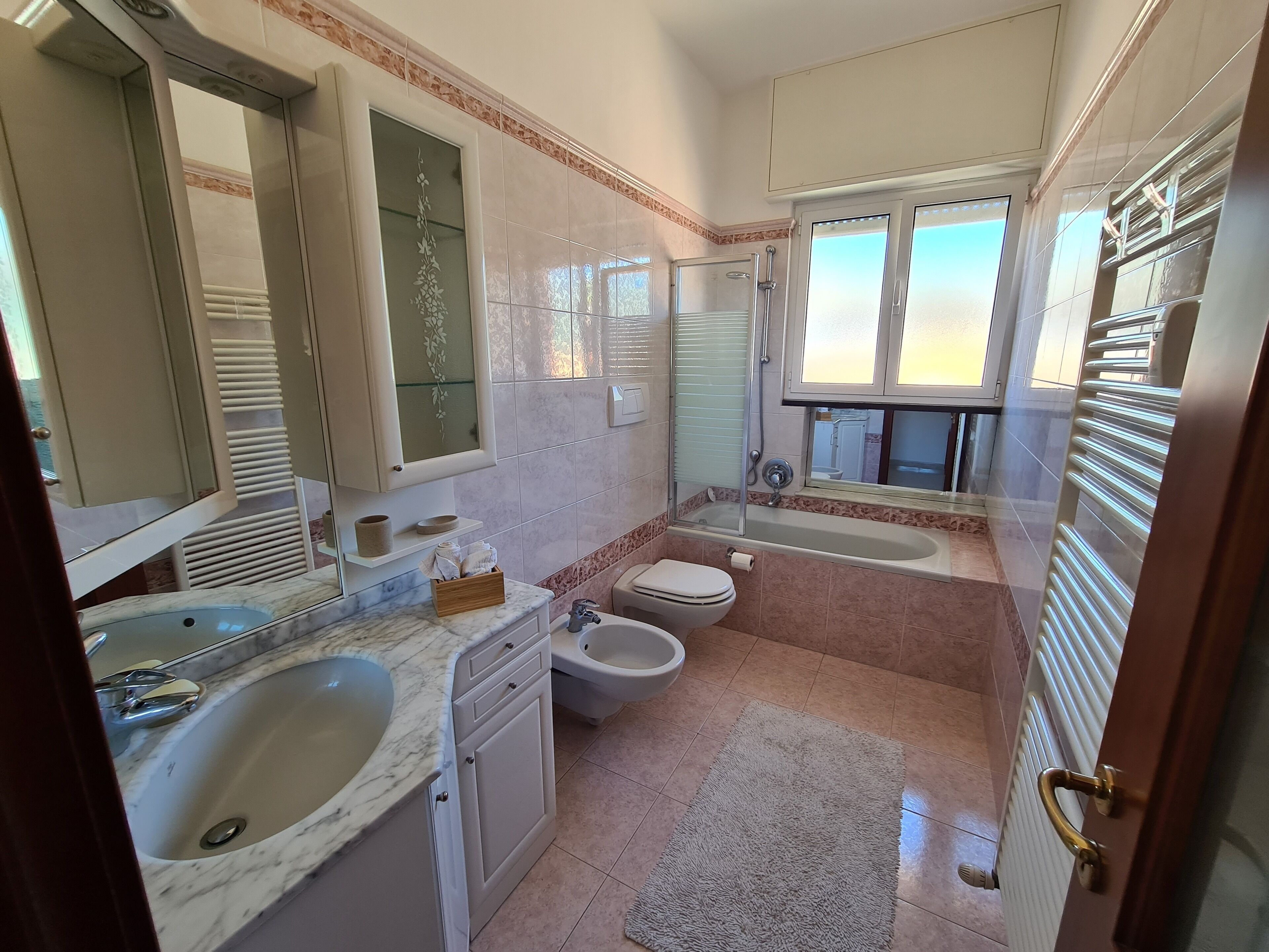 Ein Badezimmer mit Marmorwaschbecken, Toilette, Badewanne und Dusche.