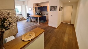 Une cuisine moderne avec des meubles de couleur sombre, une table à manger en bois et un petit îlot central doté d’un évier.
