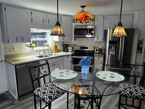 Una cocina moderna con una isla central, electrodomésticos de acero inoxidable y elegantes lámparas colgantes de vidrio artístico.