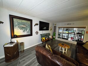 Una sala de estar con un cuadro grande, un televisor, un sofá, una mesa de centro y una ventana con vista a un muelle.