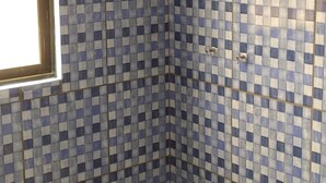 A bathroom with checkered blue and white tiles, a shower, and a toilet. - HOSTAL ETERNA PRIMAVERA  (Copacabana)