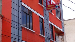 A multi-story building with a red facade and white window frames. A signboard for 'Hostal Estrella Primavera' is visible on the building. - HOSTAL ETERNA PRIMAVERA  (Copacabana)
